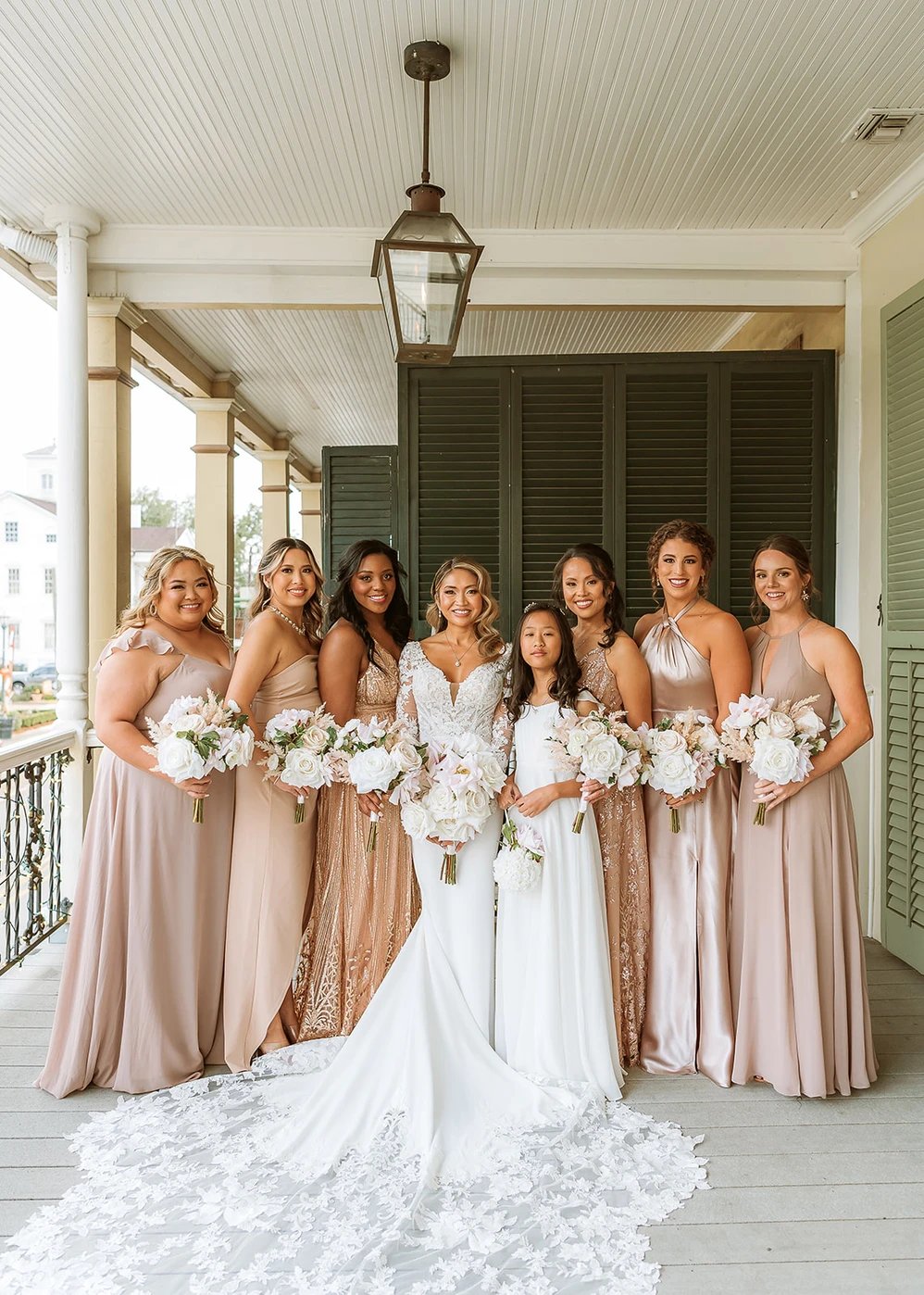 Bride and bridesmaids in blush gowns on balcony porch at Maison De Tours historic wedding venue Saint Martinville Louisiana