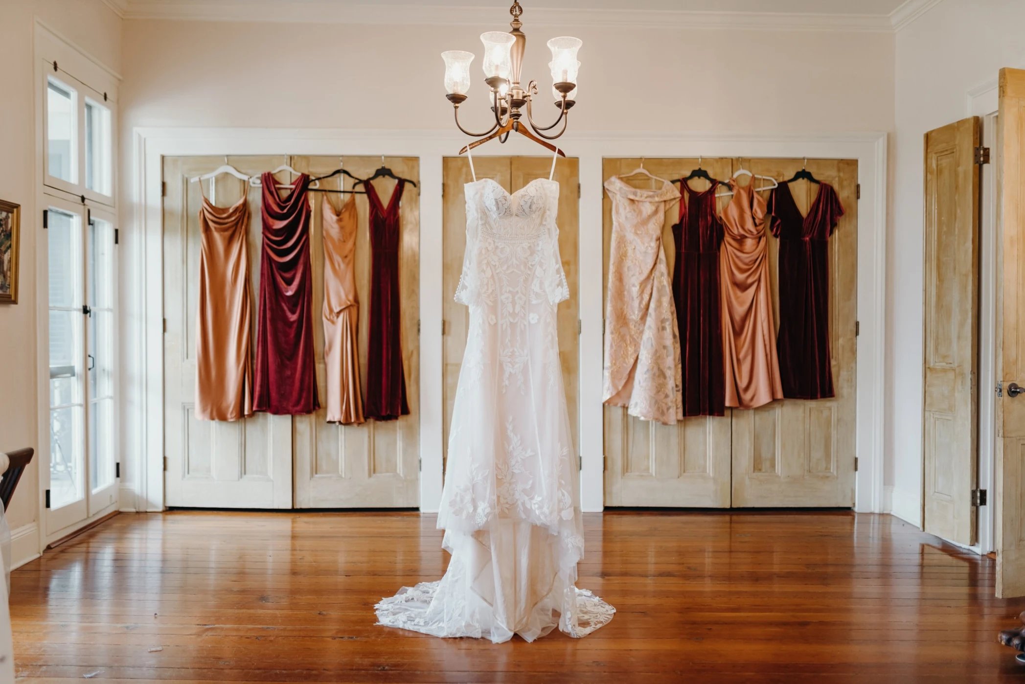 Wedding dress and bridesmaids gowns hanging in bridal suite at Maison De Tours historic venue Saint Martinville Louisiana