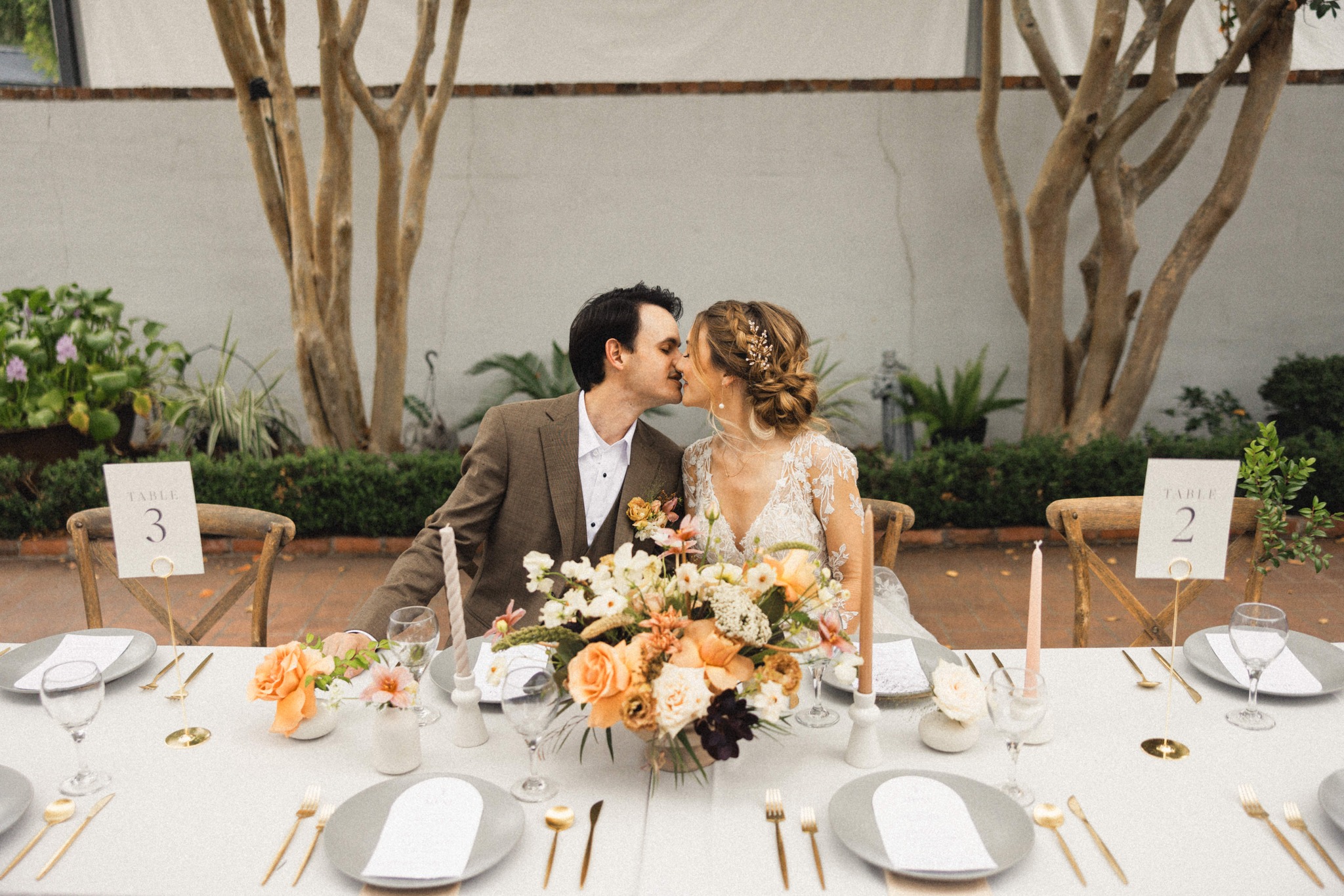 Bride and groom kissing at sweetheart table with floral centerpieces at Maison De Tours wedding reception Saint Martinville Louisiana