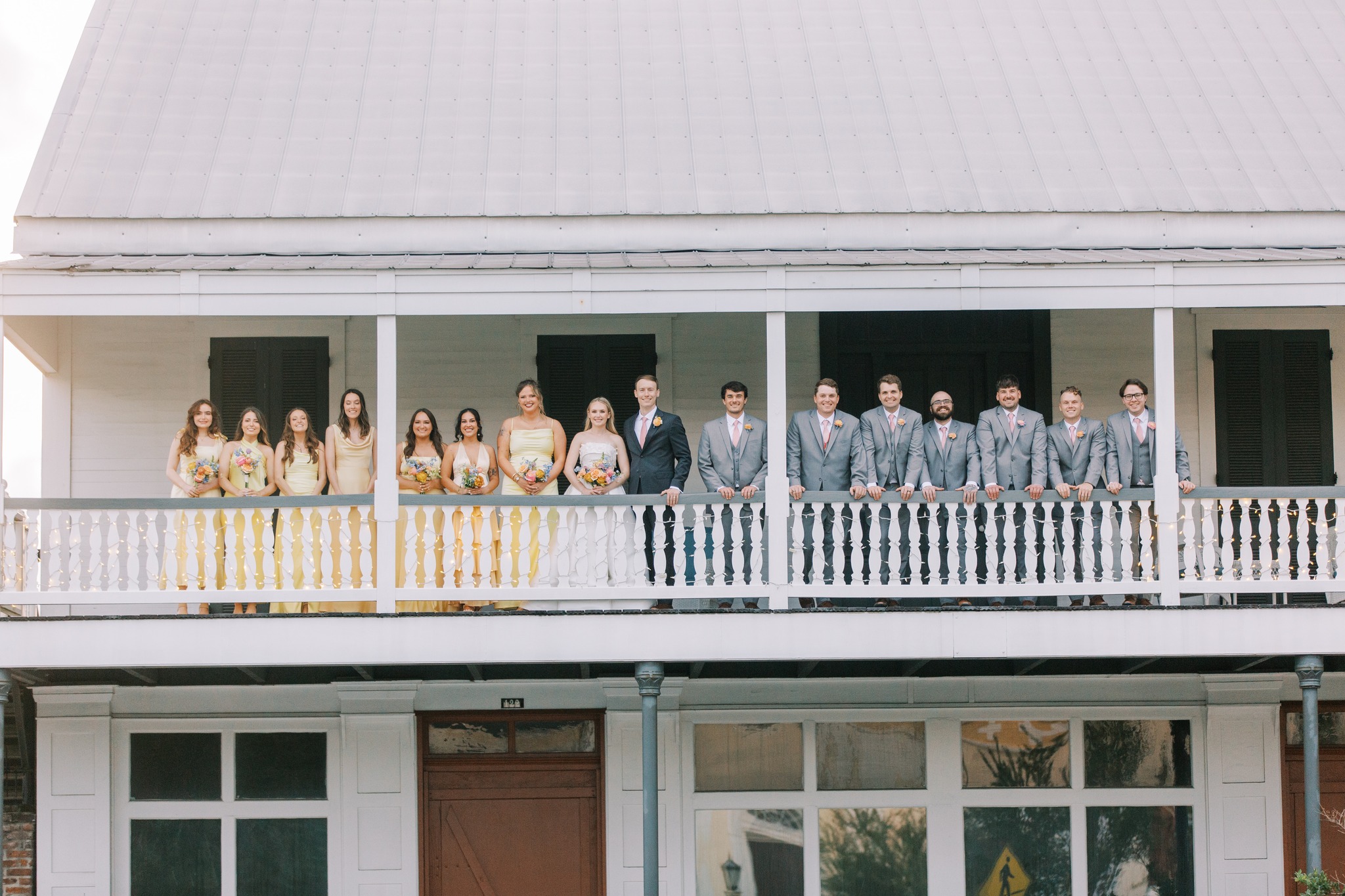 Full wedding party on balcony of Maison De Tours historic venue Saint Martinville Louisiana