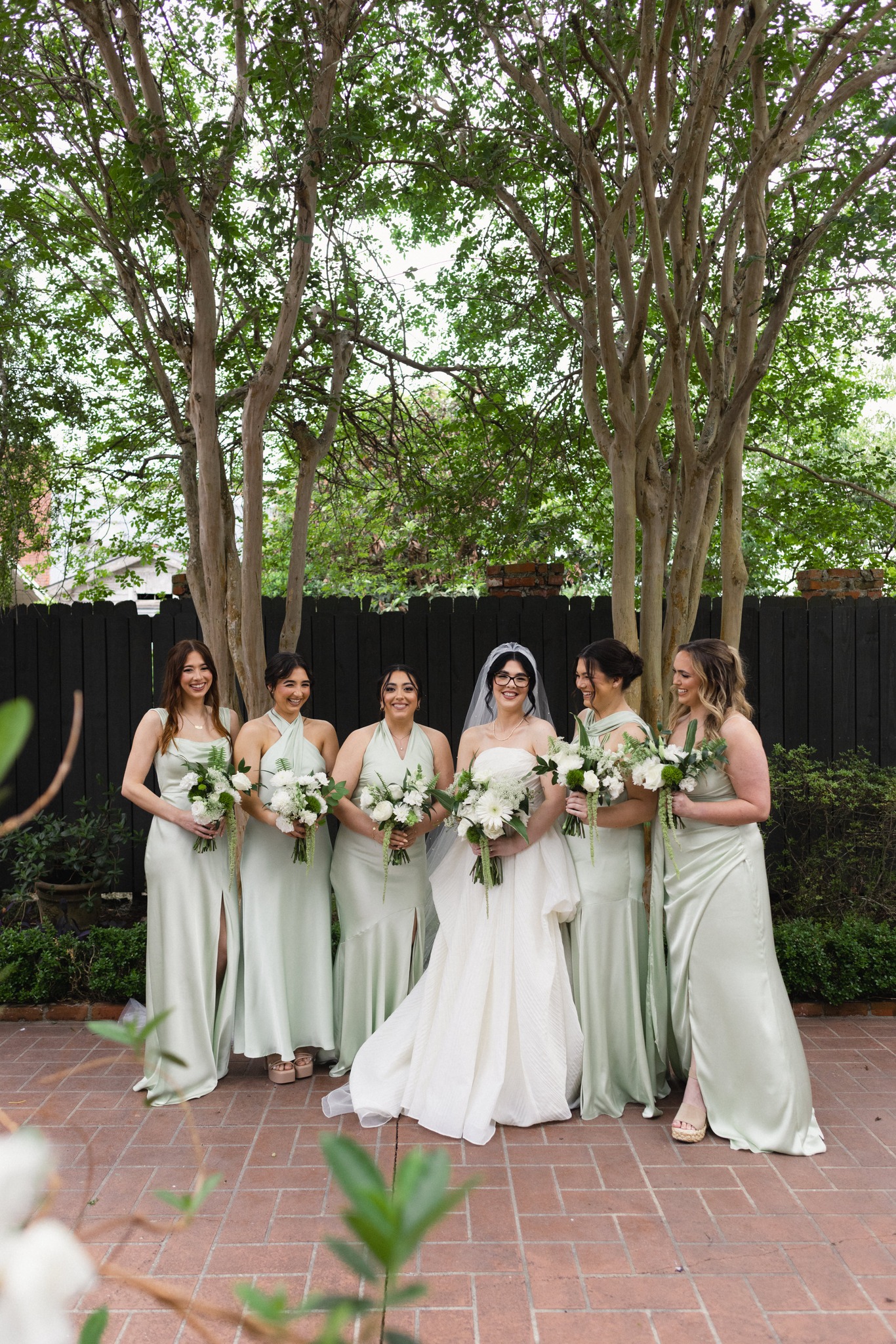 Bridesmaids in sage green gowns in courtyard at Maison De Tours wedding venue Saint Martinville Louisiana