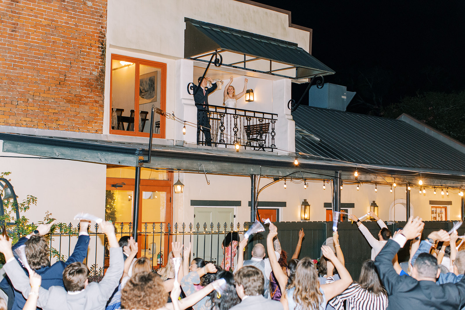 Bride and groom celebrated by guests from balcony at Maison De Tours historic event venue Saint Martinville Louisiana