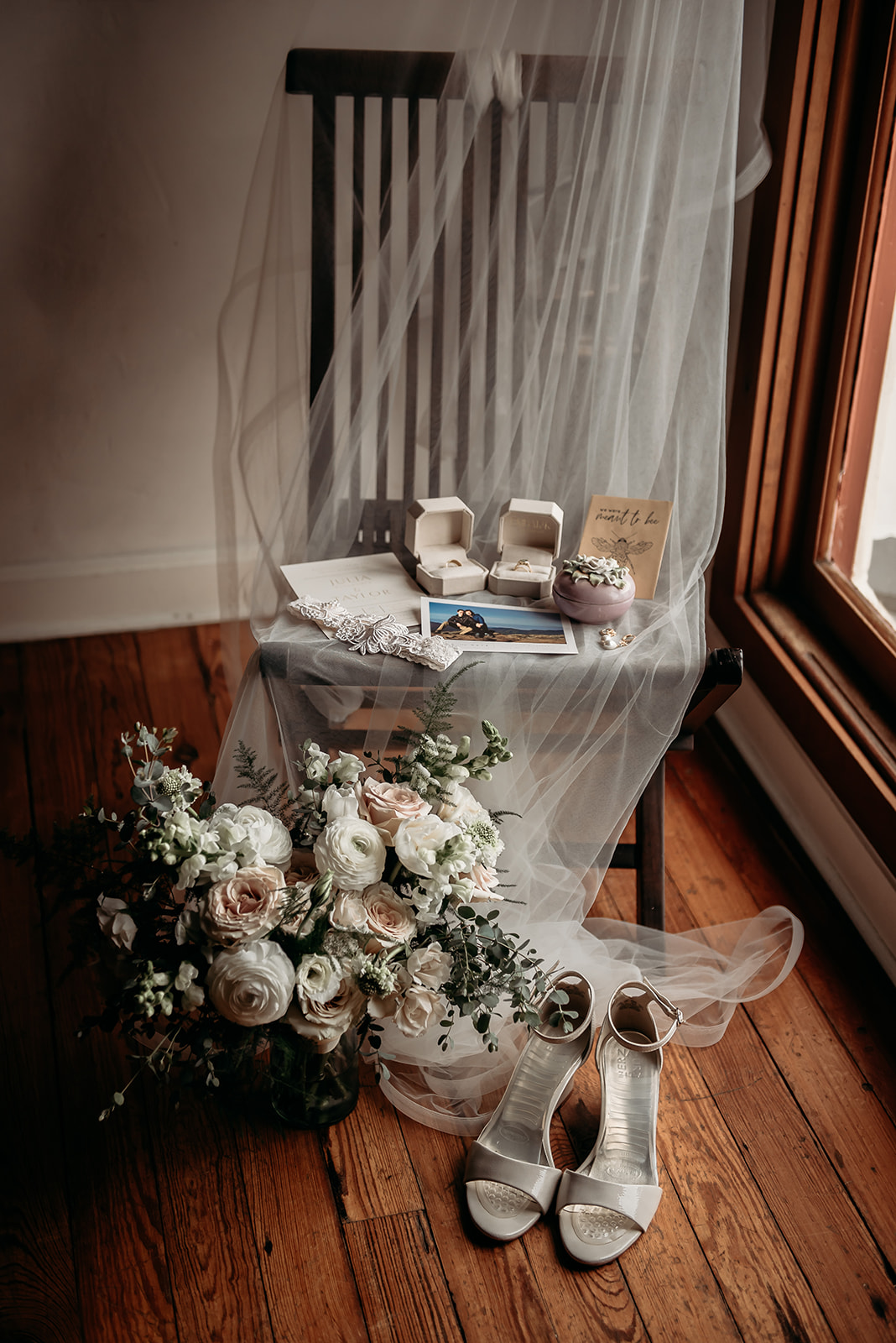 Bridal flat lay with bouquet veil shoes and rings on hardwood floors at Maison De Tours Saint Martinville Louisiana