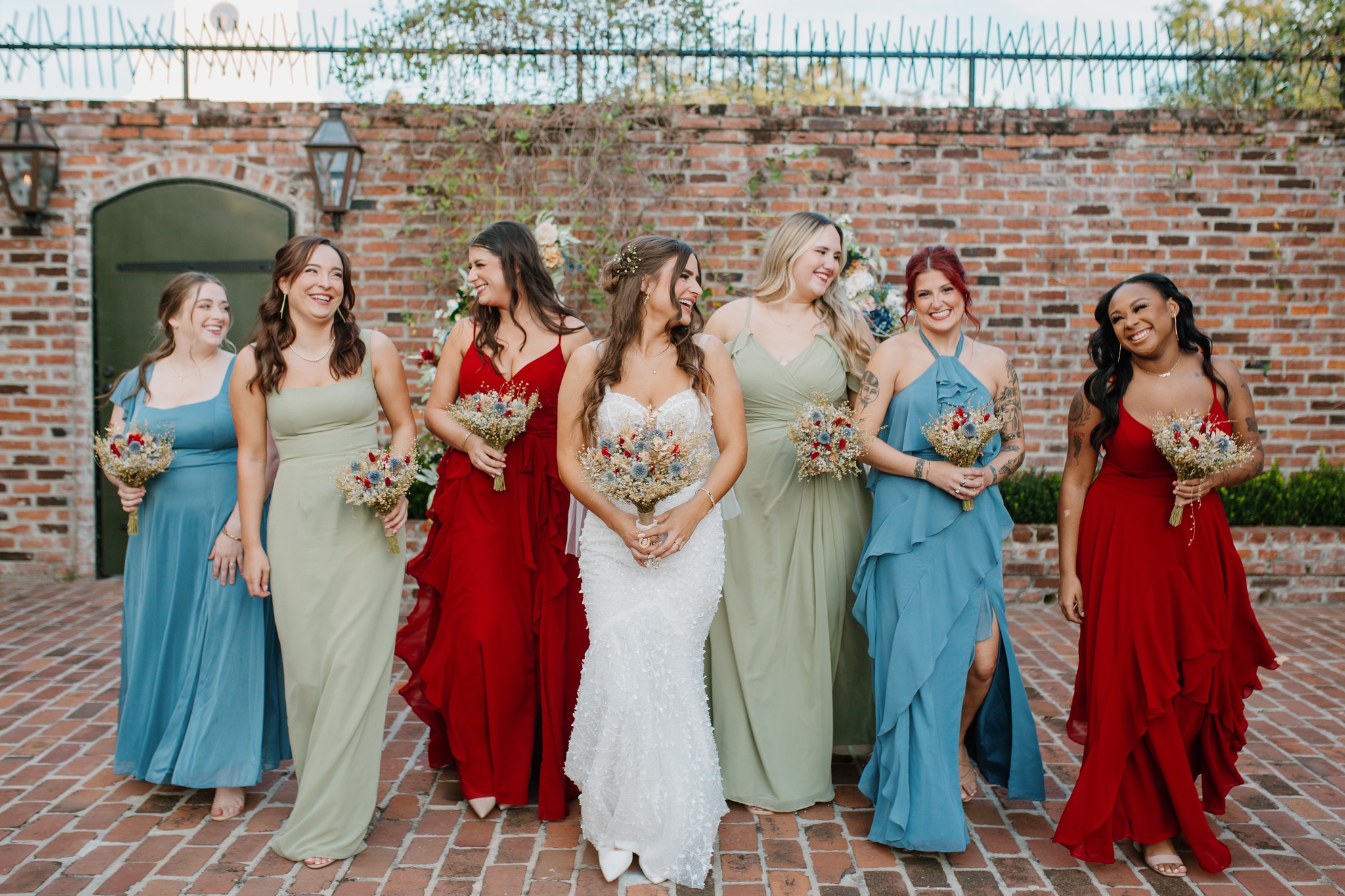 Colorful bridesmaids walking through brick courtyard at Maison De Tours historic wedding venue Saint Martinville Louisiana